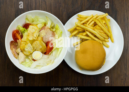 Insalata Caesar cheeseburger fries delizioso cibo sano i pomodori crostini di formaggio parmigiano e mozzarella fresca junk food fast food carne formaggio bad foo Foto Stock