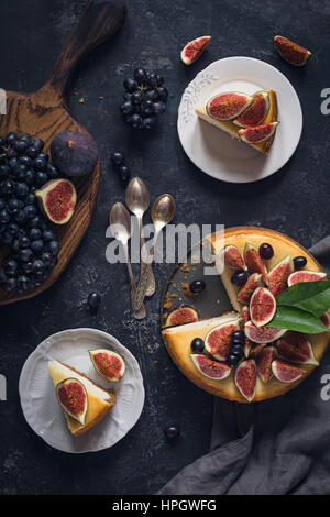 Cheesecake decorati con frutta fresca (fichi e uva). Vista superiore, piatto laici. Alimentare la vita ancora Foto Stock