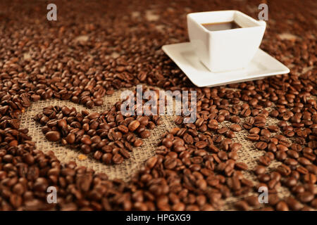 Amore di caffè dal marrone caffè in grani con il bianco tazza di caffè Foto Stock