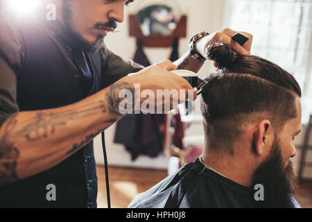 Immagine ravvicinata dell'uomo diventando taglio di capelli alla moda al Barber shop. Parrucchiere maschio serve client, rendendo haircut utilizzando la macchina e il pettine. Foto Stock