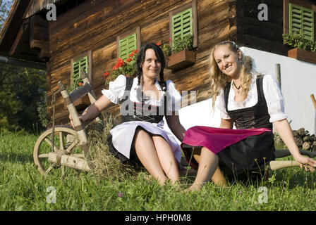 Modello rilasciato , Zwei junge Frauen im Dirndl mit Schubkarre - donne in dirndl con carriola Foto Stock