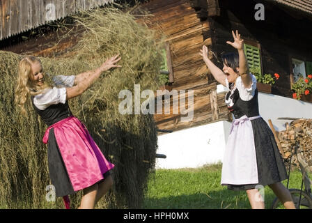 Modello rilasciato , Zwei junge Frauen im Dirndl bei der Heuarbeit - donne in dirndl fare il fieno raccolto Foto Stock