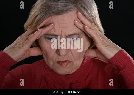 Triste donna matura in rosso su sfondo nero Foto Stock