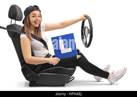 Felice ragazza con un'L-segno e fingendo di guidare in un sedile di automobile isolato su sfondo bianco Foto Stock