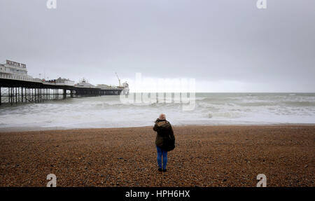 Una donna che guarda il mare sulla spiaggia di Brighton, East Sussex, come le perturbazioni atmosferiche inizia prima della tempesta di predizione Doris domani. Foto Stock