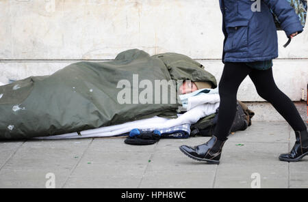 Senzatetto uomo dorme grezzo su strade di Brighton come passer da passeggiate passato Foto Stock