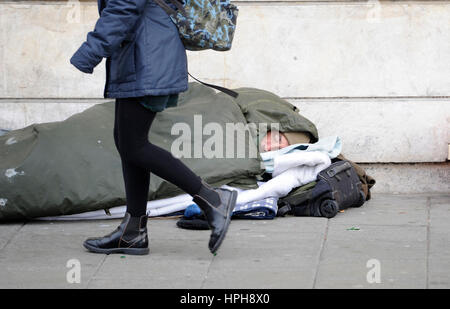 Senzatetto uomo dorme grezzo su strade di Brighton come passer da passeggiate passato Foto Stock