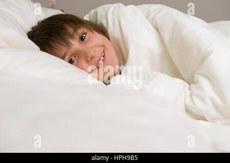 Kleiner Junge liegt froehlich im Bett - boy fortunato nel letto, Modello rilasciato Foto Stock