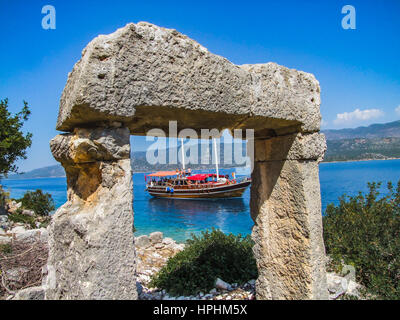 Blu barca crociera passando per le persone di isola in barca guardando l'isola e rovine, mavi yolculuk teknesi. barca sul blu satinato mare,fethiye Foto Stock