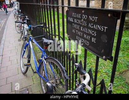 Biciclette bloccato ad una ringhiera sotto una Non parcheggiare le biciclette contro le ringhiere segno, in Oxford Foto Stock