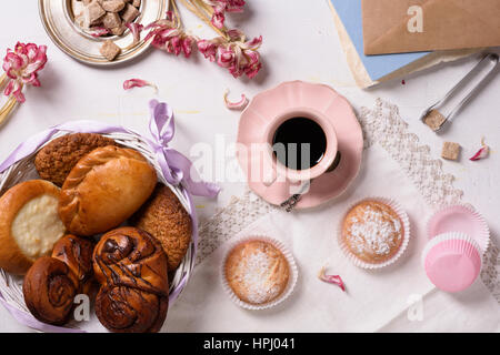 Pasticceria fresca con caffè, tortine, rosa tulip fiori rustico su sfondo bianco. Vista superiore, la luce del mattino. Foto Stock
