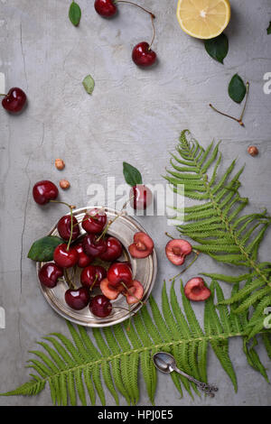 Dolce di ciliegie rosse su sfondo grigio. Vista superiore, copia dello spazio. Foto Stock