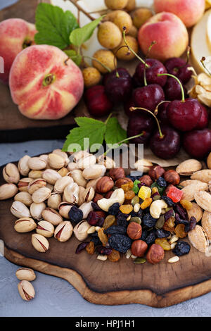 Frutta fresca e un dado piatto con ciliegia, pesche e trail mix Foto Stock