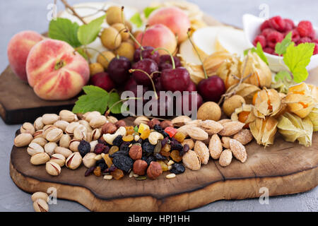 Frutta fresca e un dado piatto con ciliegia, pesche e trail mix Foto Stock