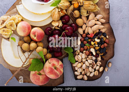 Frutta fresca e un dado piatto con ciliegia, pesche e trail mix Foto Stock