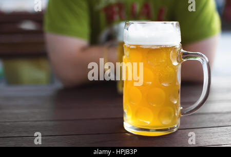 Di vetro tappata la birra artigianale. Lager non filtrata su un tavolo da pub. Uomo in background. Profondità di campo Foto Stock