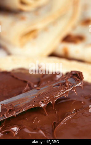 La colazione fotografia di spalmatura a coltello pasta cioccolato su un pancake. Macro leggera profondità di campo Foto Stock