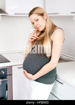 Donna incinta di fumare sigarette a casa Foto Stock