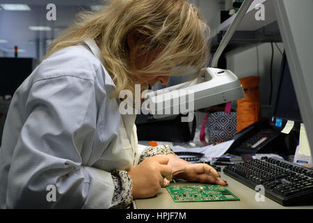 Lavoratore di sesso femminile che il montaggio di una scheda di circuito in corrispondenza di una fabbrica di componenti elettronici Foto Stock