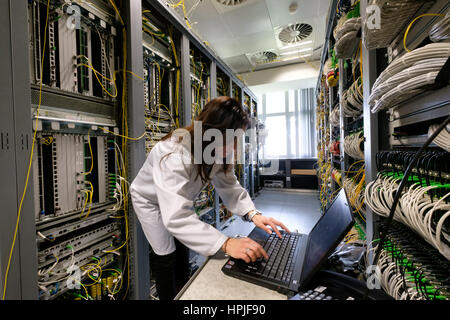 Ingegnere femmina su laptop che fissa alcuni problemi in una sala server Foto Stock
