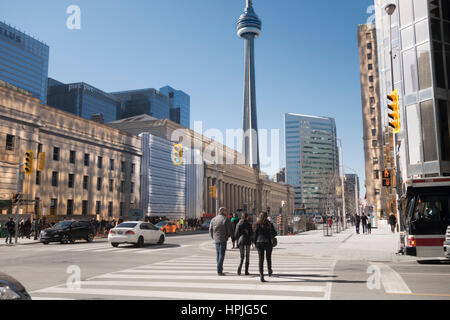 Persone che attraverso un crosswalk sul lato anteriore e la baia di San da Union Station con la CN Tower in background. Foto Stock