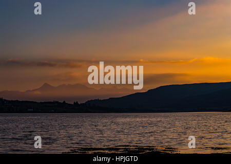 Cuillin Hills Mountain Range, sul Loch Portree, sull'Isola di Skye in Scozia, contro un cielo drammatico in tarda serata sole riflessioni di molti colori Foto Stock