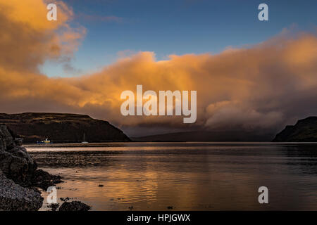 Vista del suono Rassay da Loch Portree, Isola di Skye in Scozia, come il sole stava andando per la sera. Il sole arancione riflettente, con arcobaleno. Foto Stock