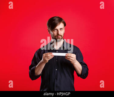 Uomo con un vuoto copyspace. Spazio pubblicitario. Attraente uomo con sguardo serio tenendo un cartello con entrambe le mani. Foto Stock