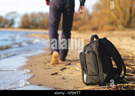 L'uomo ha lasciato il suo zaino e camminare sulla spiaggia Foto Stock