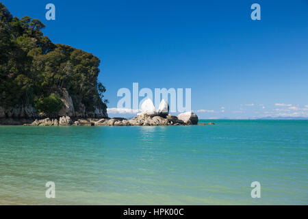 Kaiteriteri, Tasmania, Nuova Zelanda. Vista di Split Rock Apple attraverso le acque turchesi della baia di torri. Foto Stock