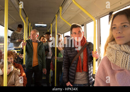 Persone diverse possono essere visto in piedi e seduti in un bus. Alcuni stanno parlando, altri stanno guardando fuori dalla finestra. Foto Stock