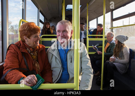 Coppia senior che viaggiano sul bus. Ci sono altre persone sat sul bus che sono in background. Foto Stock