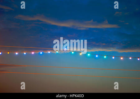 Stringa di luce colorata lampadine contro il sole di setting Foto Stock