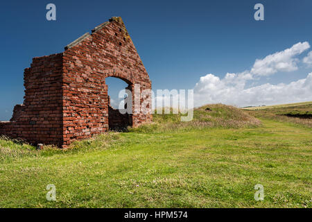 Un singolo abbandonati in mattoni rossi farm edificio sorge scoperchiata in ambiente rurale Foto Stock