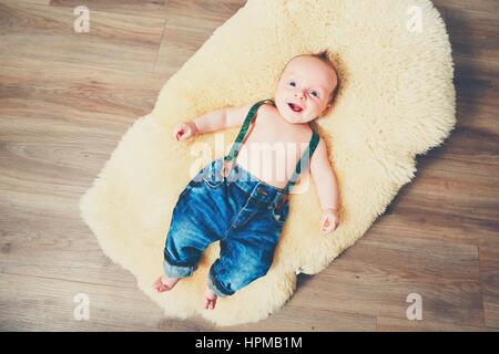 Little Boy a casa. Adorable baby poggiante sulla coperta di pelo sul legno foor. Foto Stock