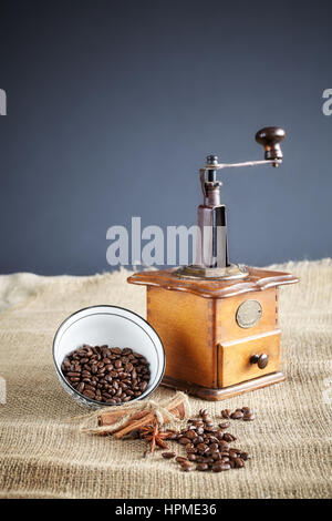 I chicchi di caffè e un vecchio macinino da caffè su sfondo di iuta, il fuoco selettivo. Foto Stock