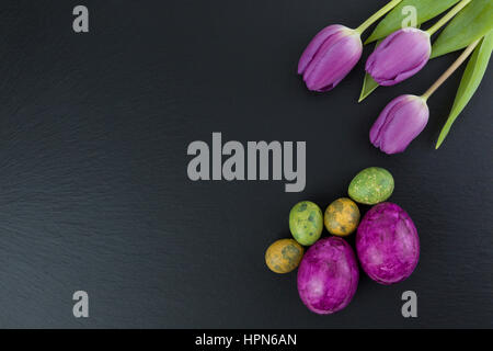 Colorata pasqua e uova di quaglia e tulip fiori sul tavolo di pietra. Vista da sopra con copia spazio. Studio shot. Foto Stock