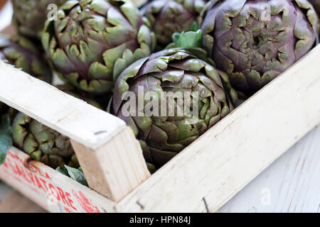 Scatola di violetta fresca carciofi close up Foto Stock