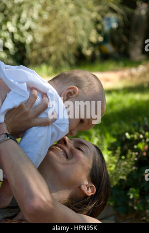 Donna giocando, baciare e amare il suo bambino sul giardino Foto Stock