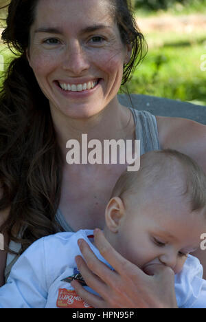 Donna giocando, baciare e amare il suo bambino sul giardino Foto Stock