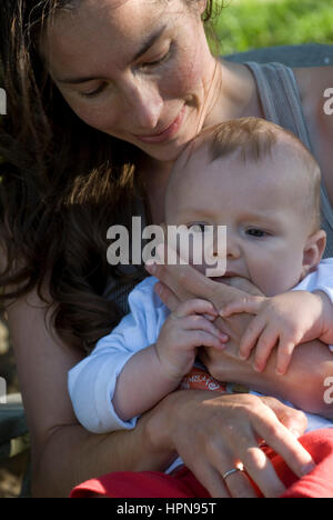 Donna giocando, baciare e amare il suo bambino sul giardino Foto Stock