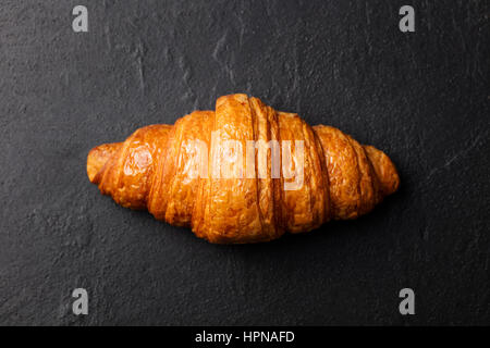 Croissant fresco su un nero ardesia sfondo. Vista dall'alto uno spazio di copia Foto Stock