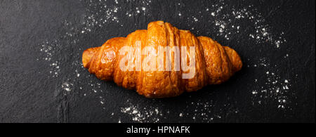 Croissant fresco su un nero ardesia sfondo. Vista dall'alto. Foto Stock