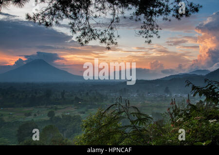 Vista in lontananza Mount Sinabung paesaggio visto al tramonto con emissione di fumo dal vertice da Gundaling Hill nel Karo highland città di Berastagi Foto Stock