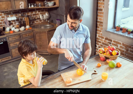 Padre e figlio facendo e di bere succo di frutta fresco Foto Stock