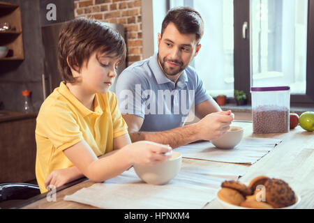 Padre e figlio seduti al tavolo di cucina e avente le sfere di cioccolato Foto Stock