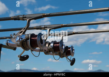 Canne da pesca con le bobine su un sistema di supporto (rod pod) e tenda turistico il campo di vacanze sulla banca. Foto Stock