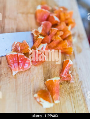 Un trito di Cara Cara arancione sul bordo di bambù con coltello Foto Stock
