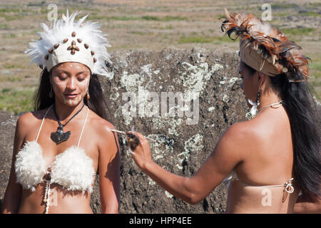 Rapa Nui danzatrice in costume tradizionale applicando body paint sulla spalla di un amico, l'Isola di Pasqua Foto Stock