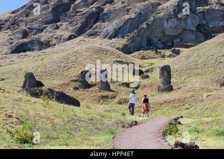 Due persone camminano lungo il sentiero attraverso la cava di moai di Rano Raraku sull'Isola di Pasqua Foto Stock